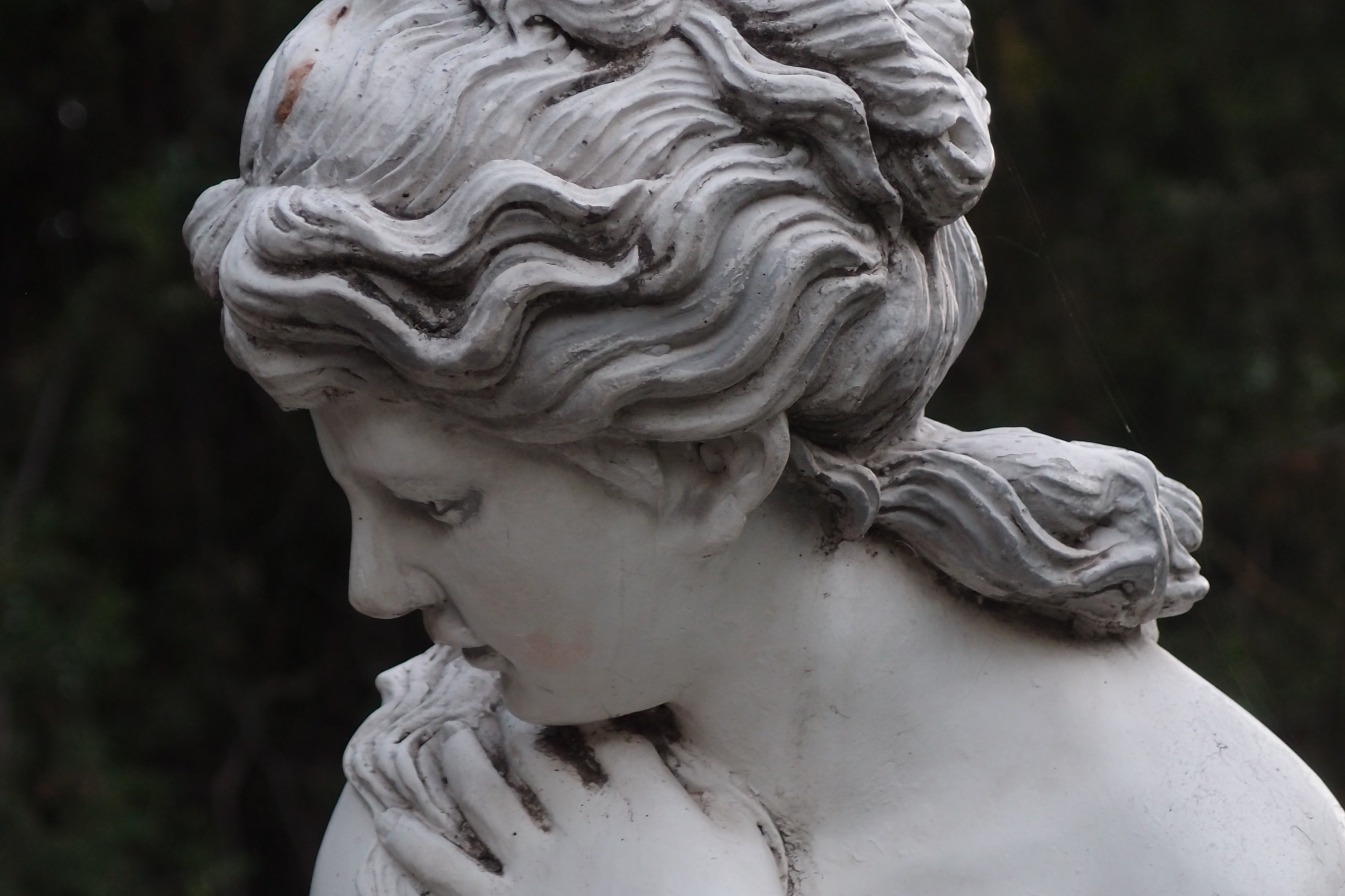 white marble statue of woman looking coyly down to the side