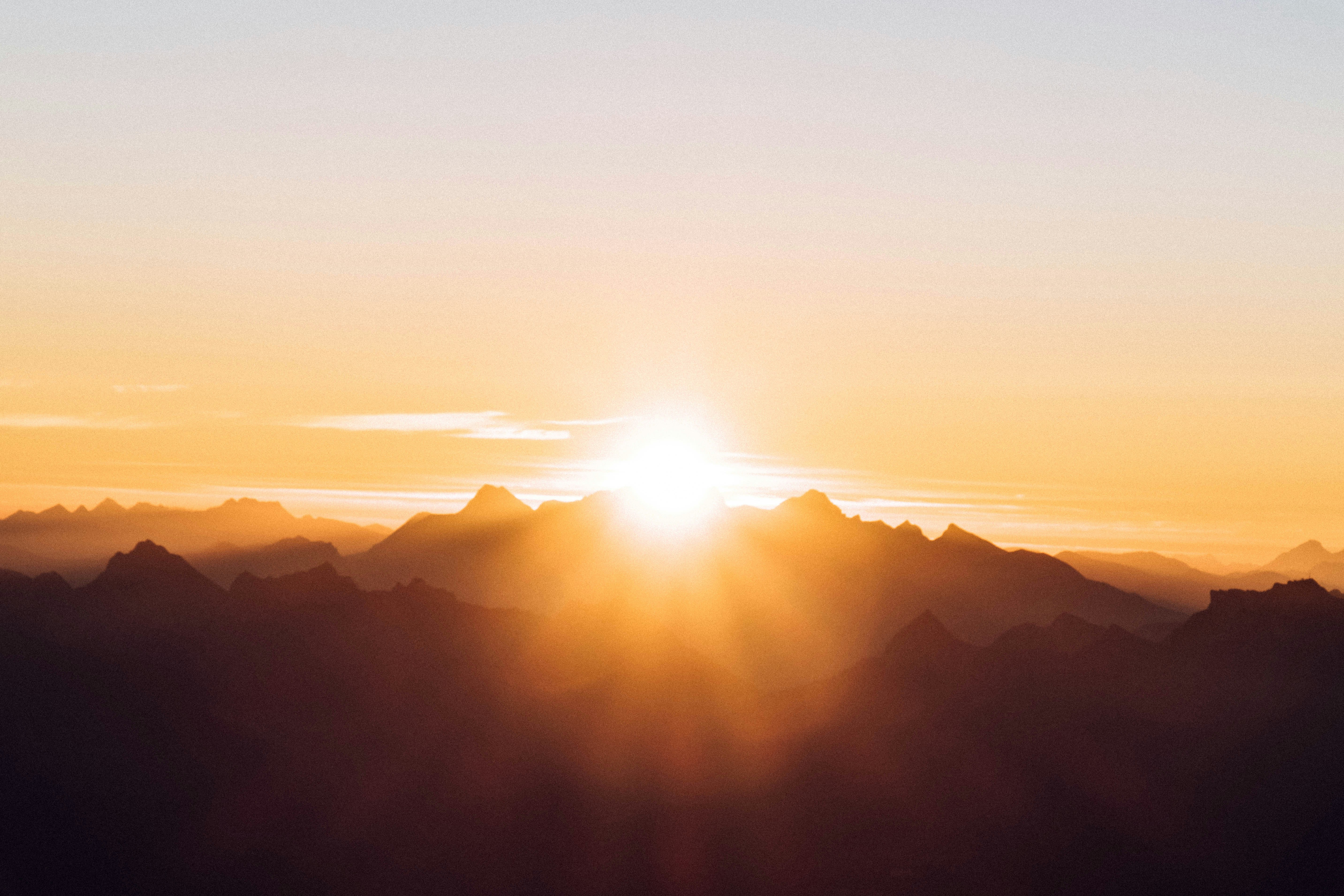 sunlight breaking over orange and yellow mountains