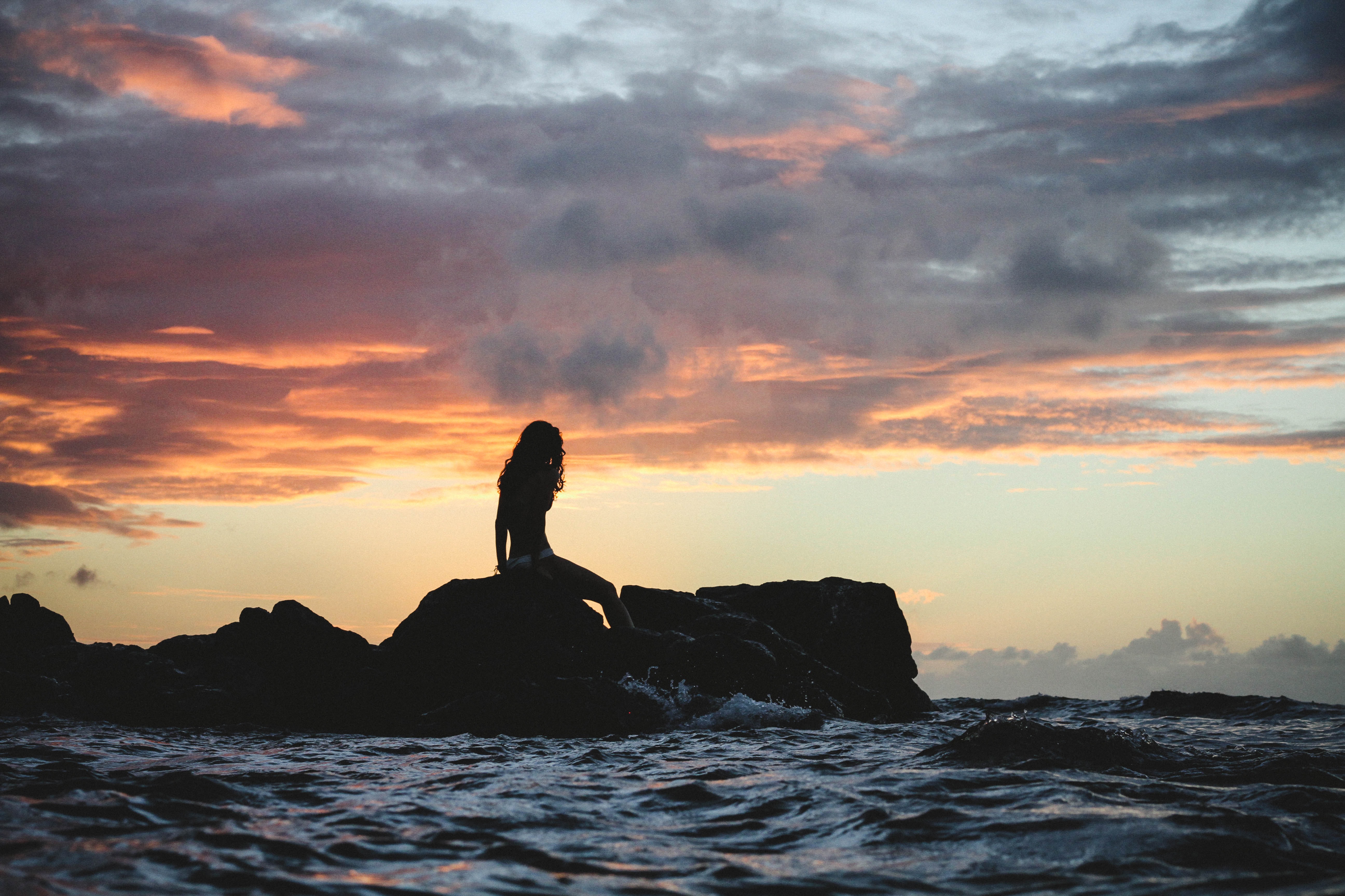 woman's silouhette under against ocean sunset