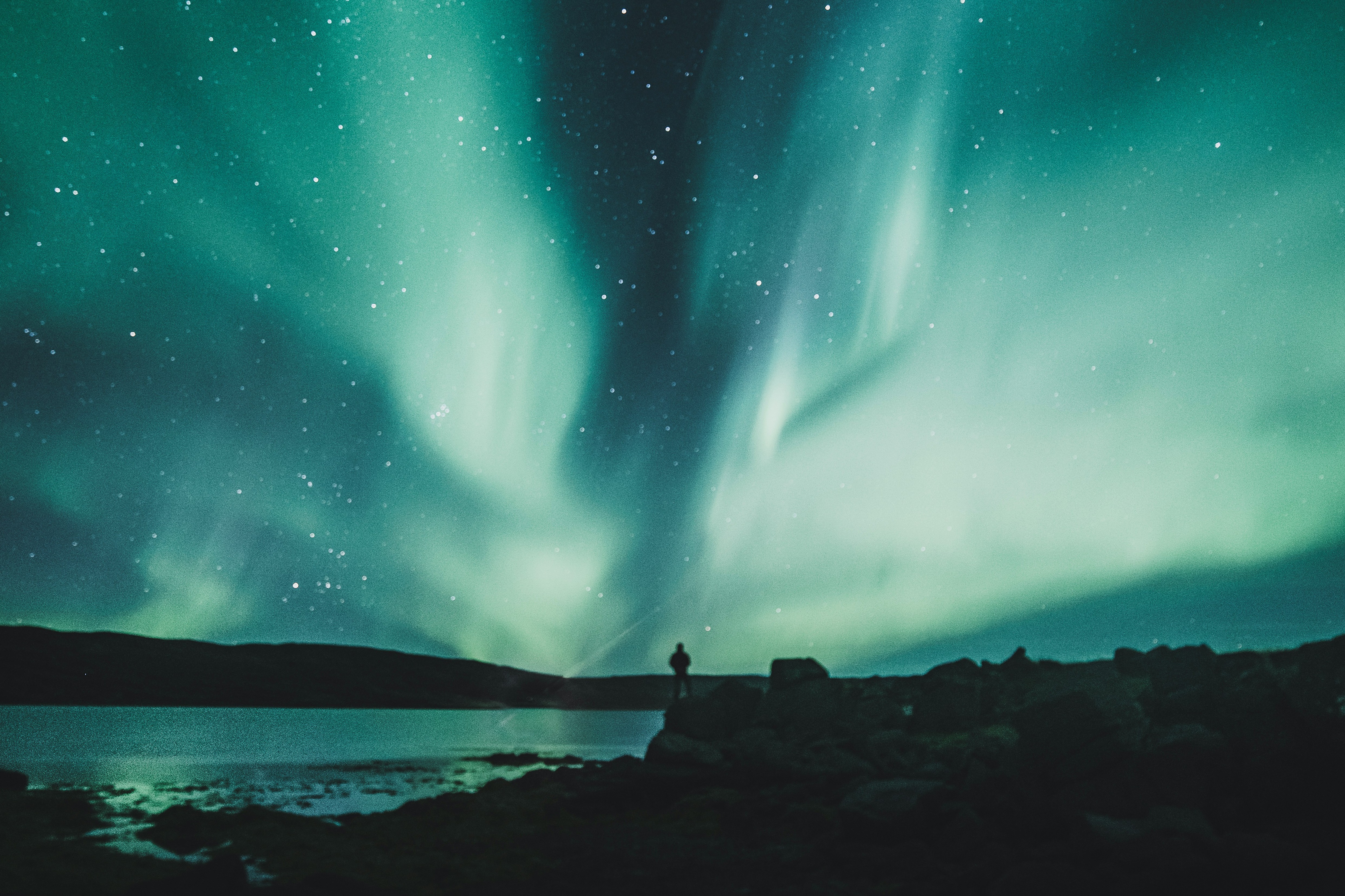 sillouhetted man watching aurora in night sky