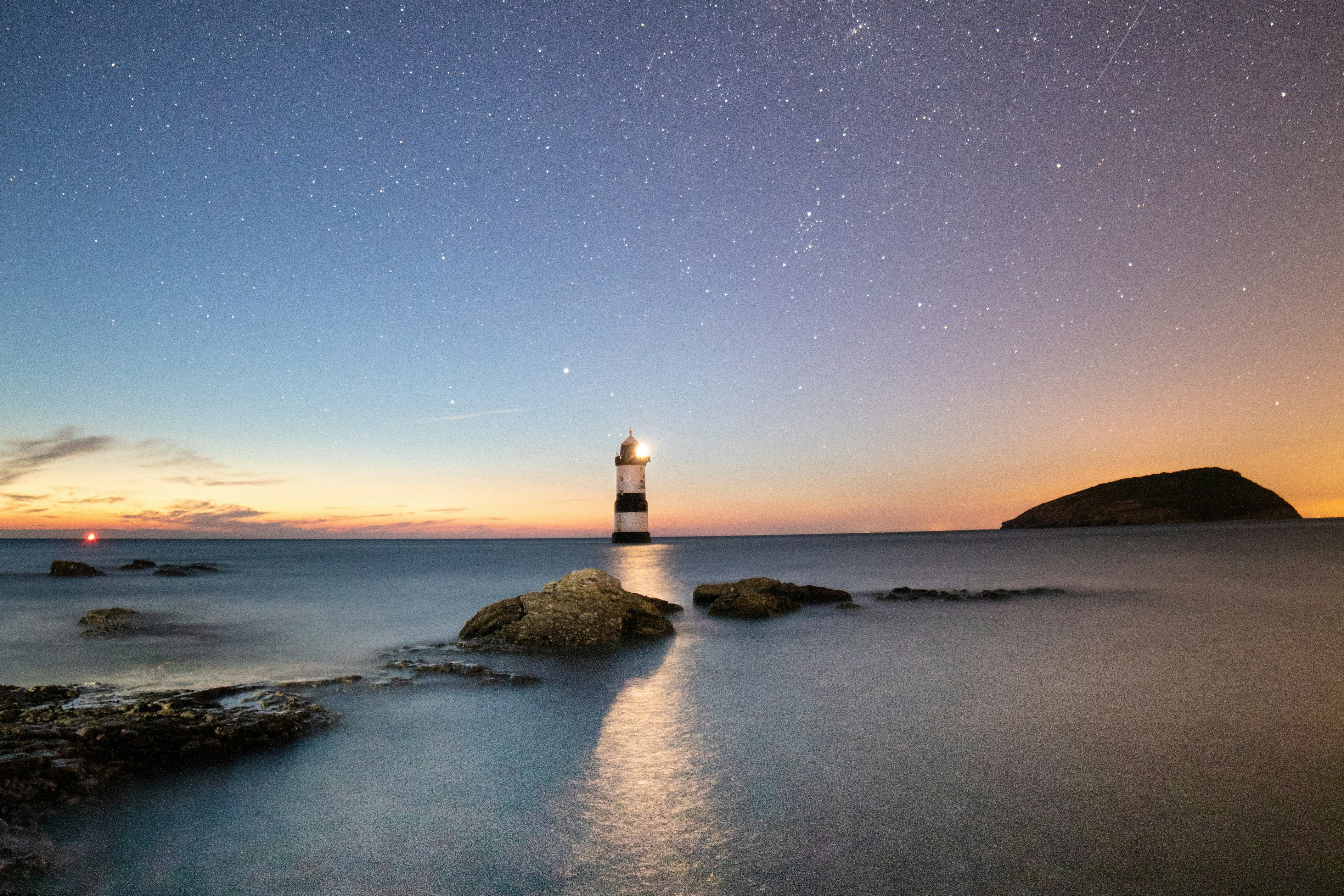 lighthouse against starry sky and sunrise