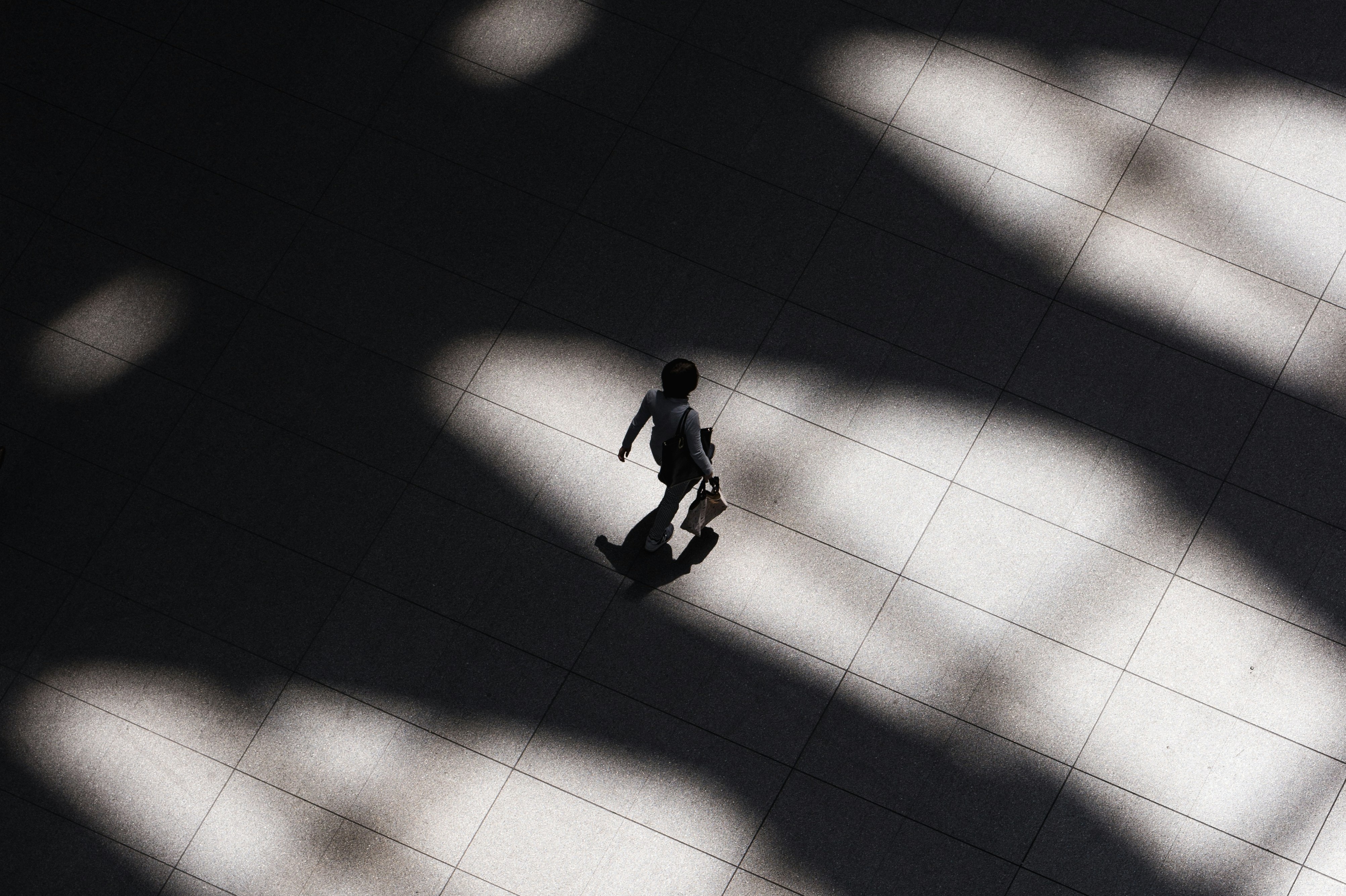 overhead b&w shot of person walking with a briefcase