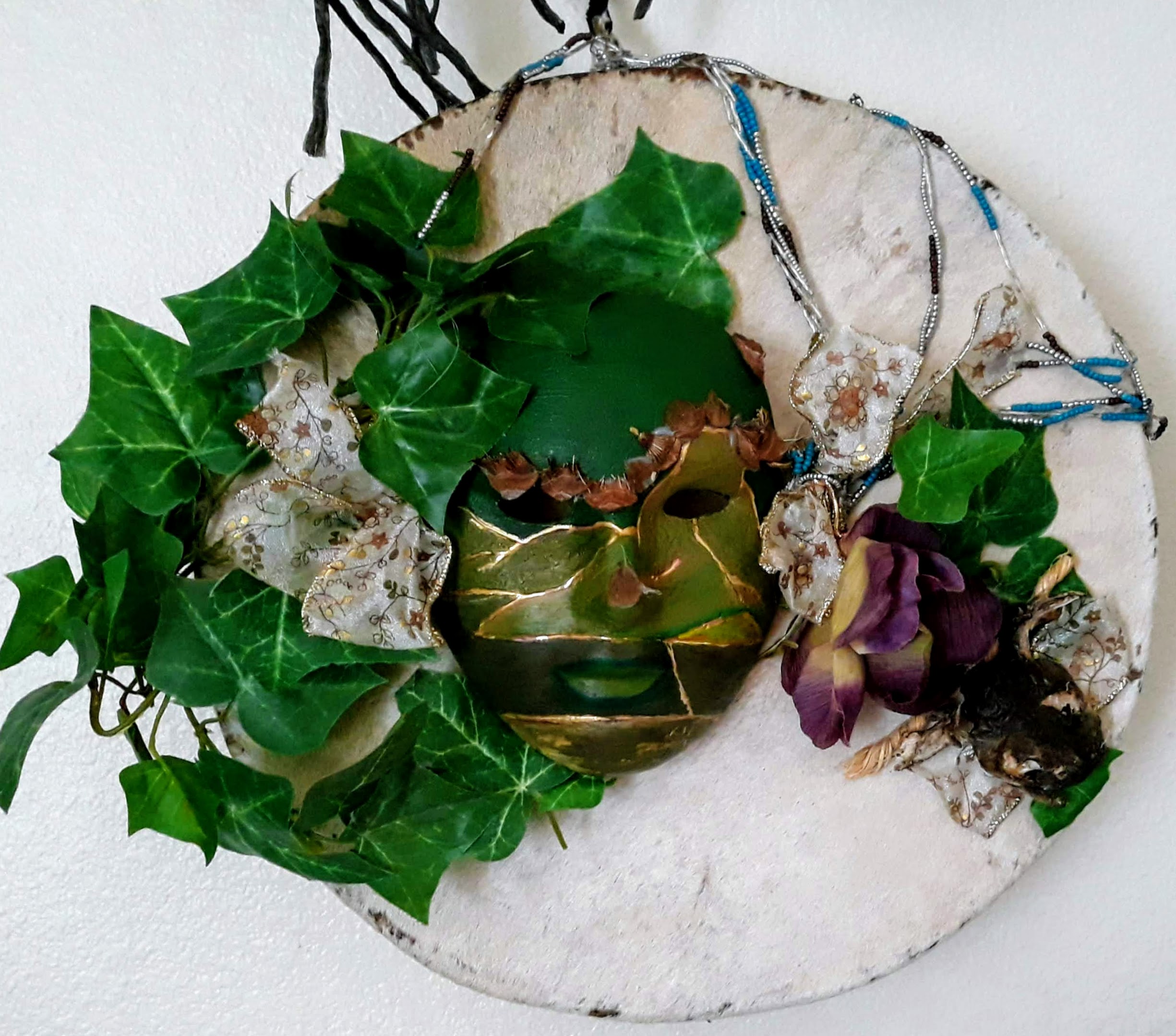 mask on drum skin with green foliage