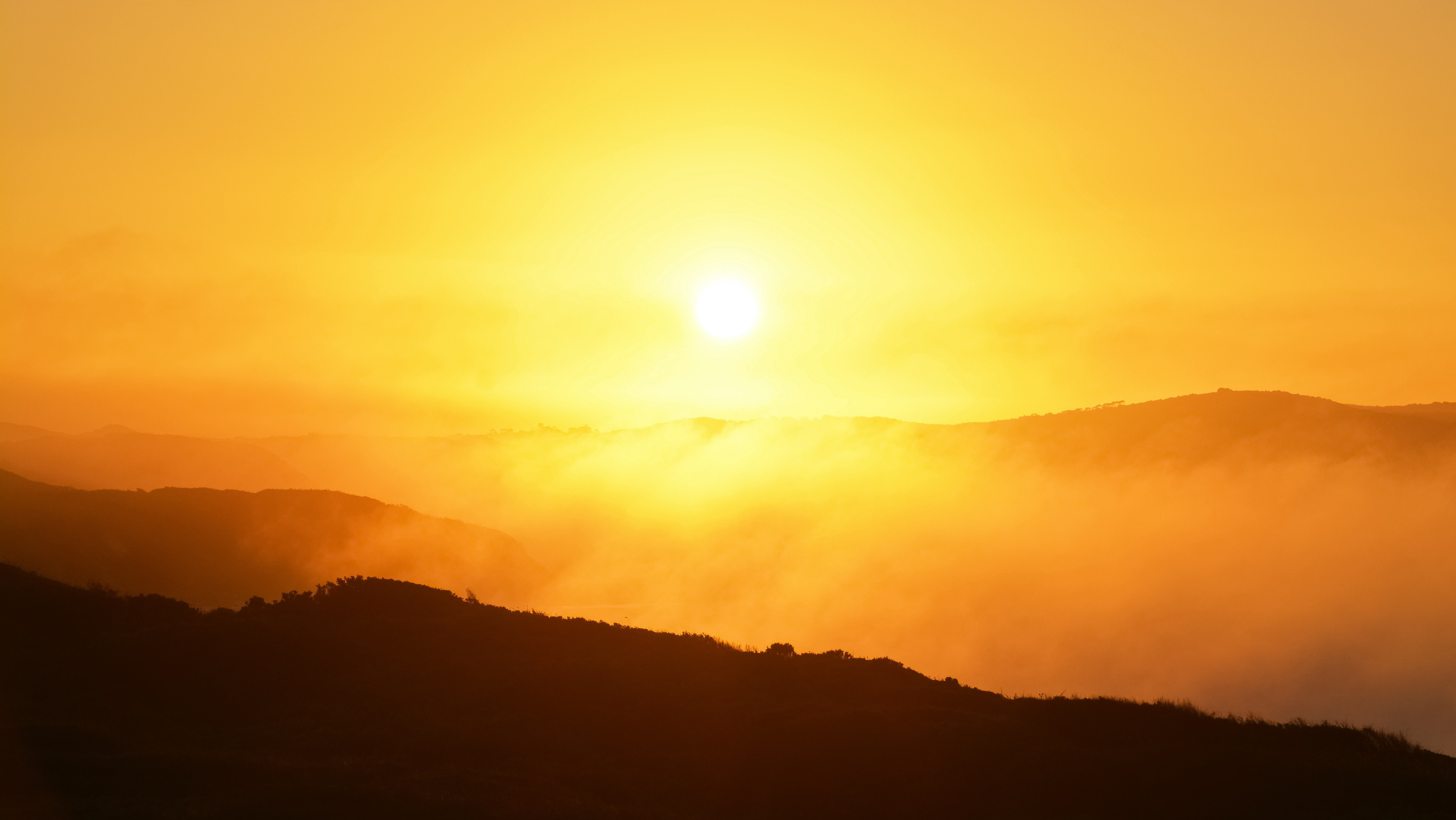 bright yellow/orange sun over mountains