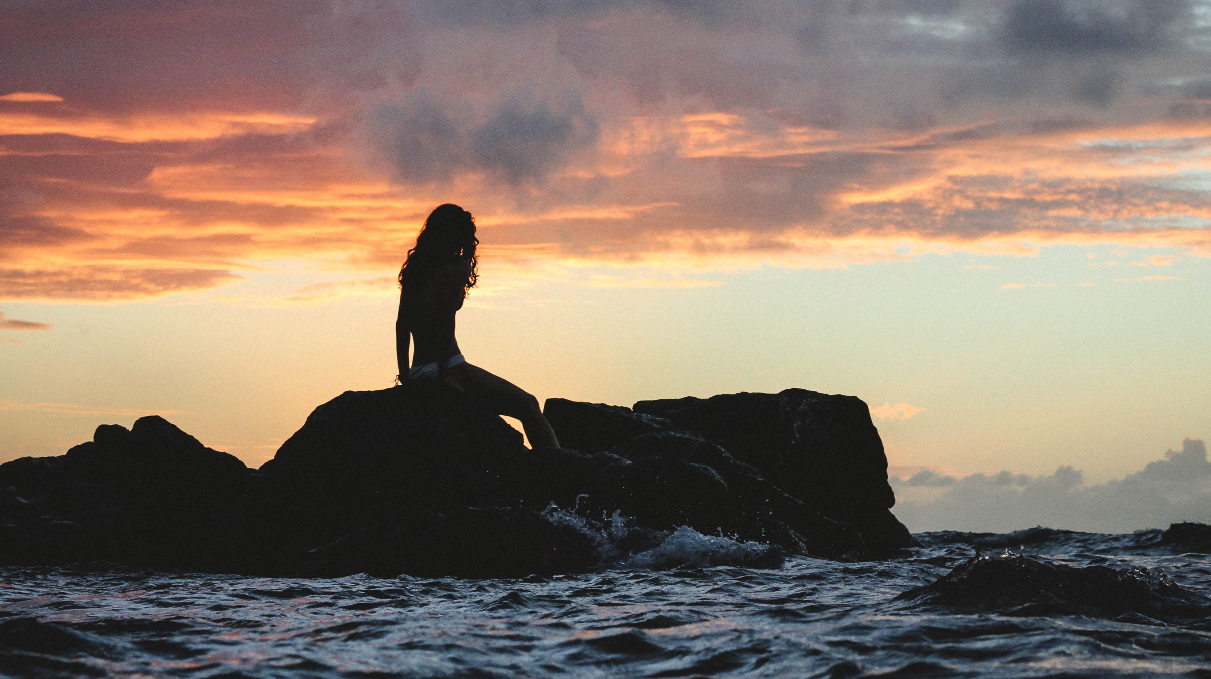 woman's silouhette under against ocean sunset