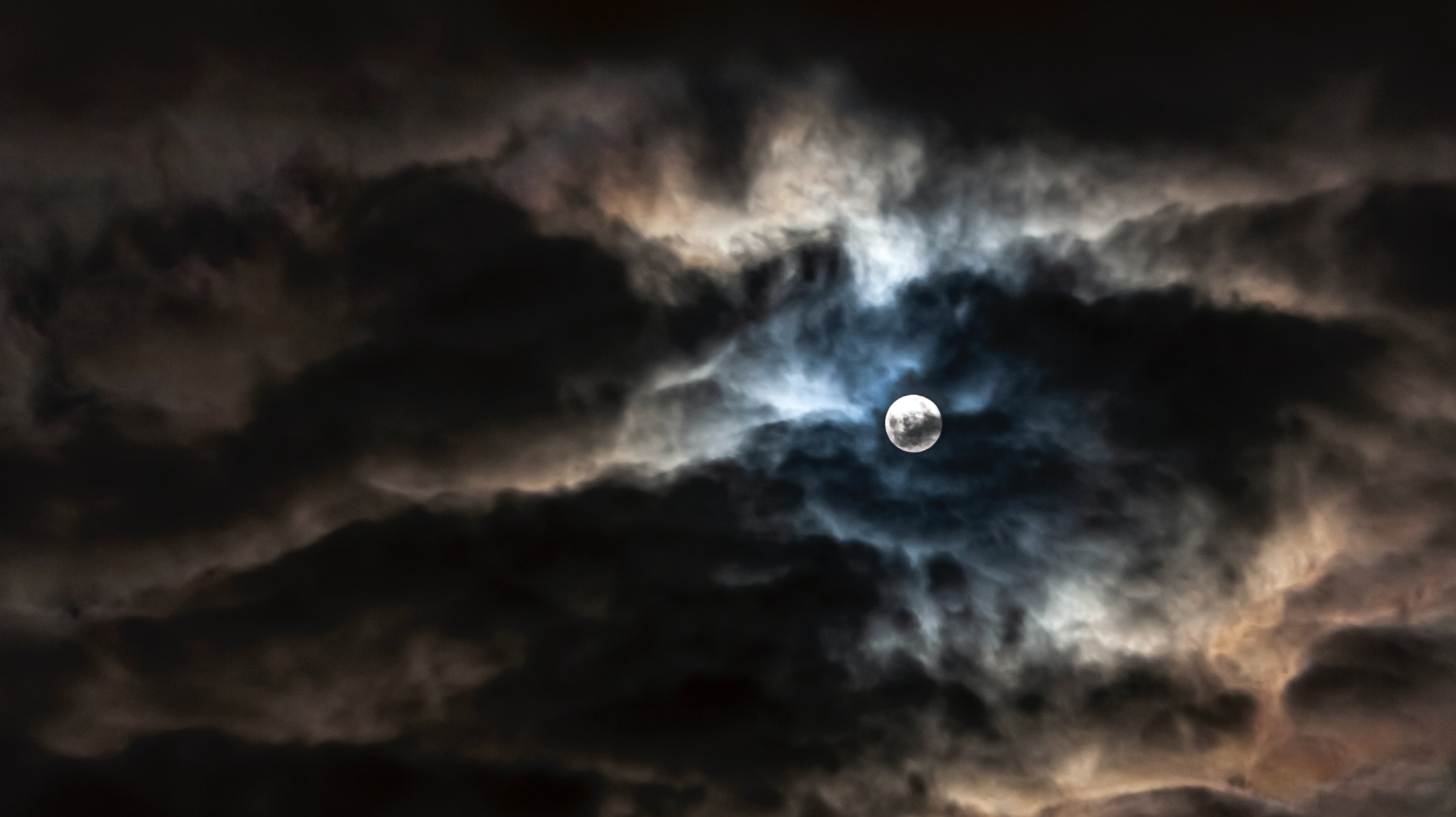 full moon breaking through dark clouds