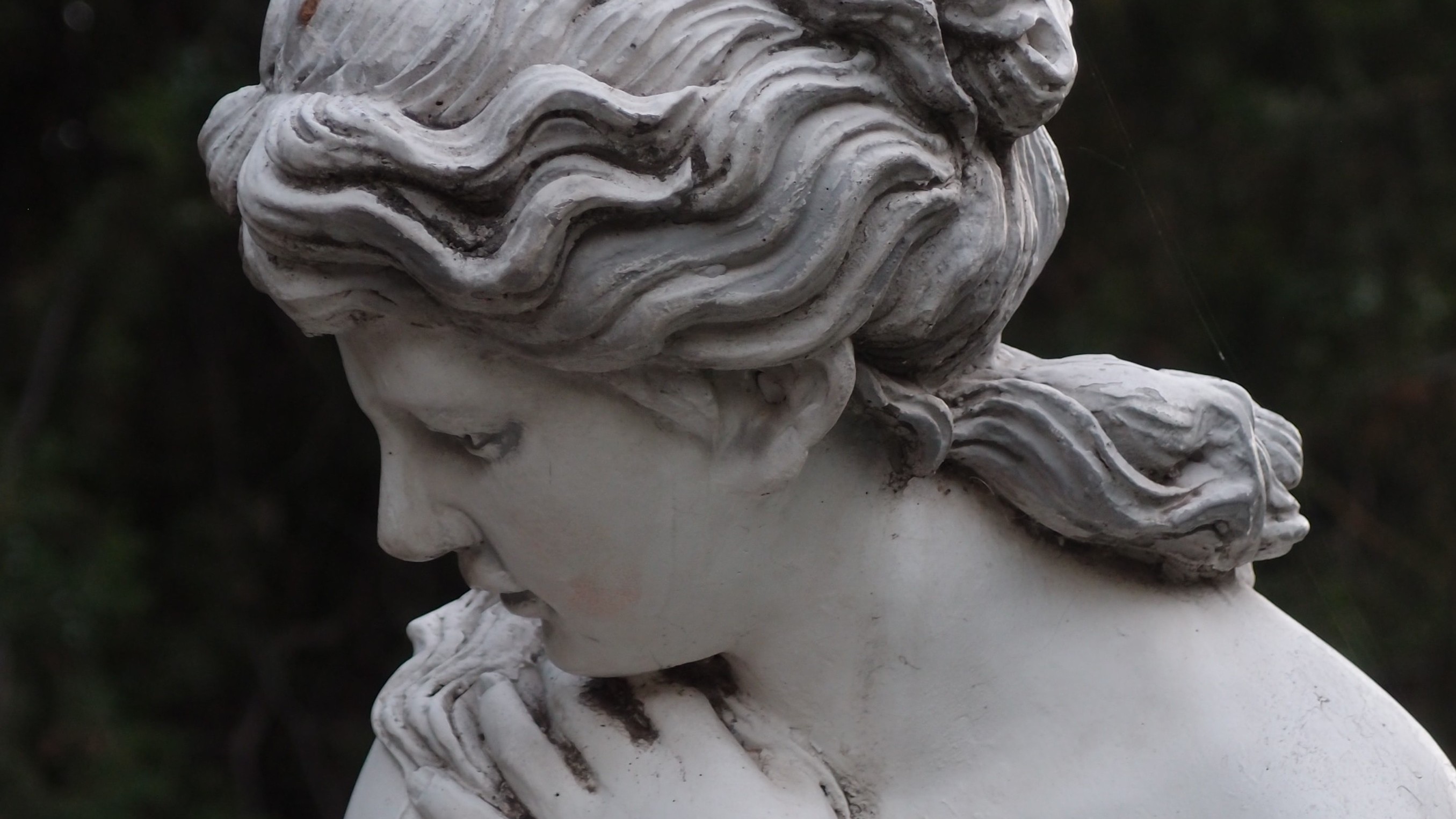 white marble statue of woman looking coyly down to the side