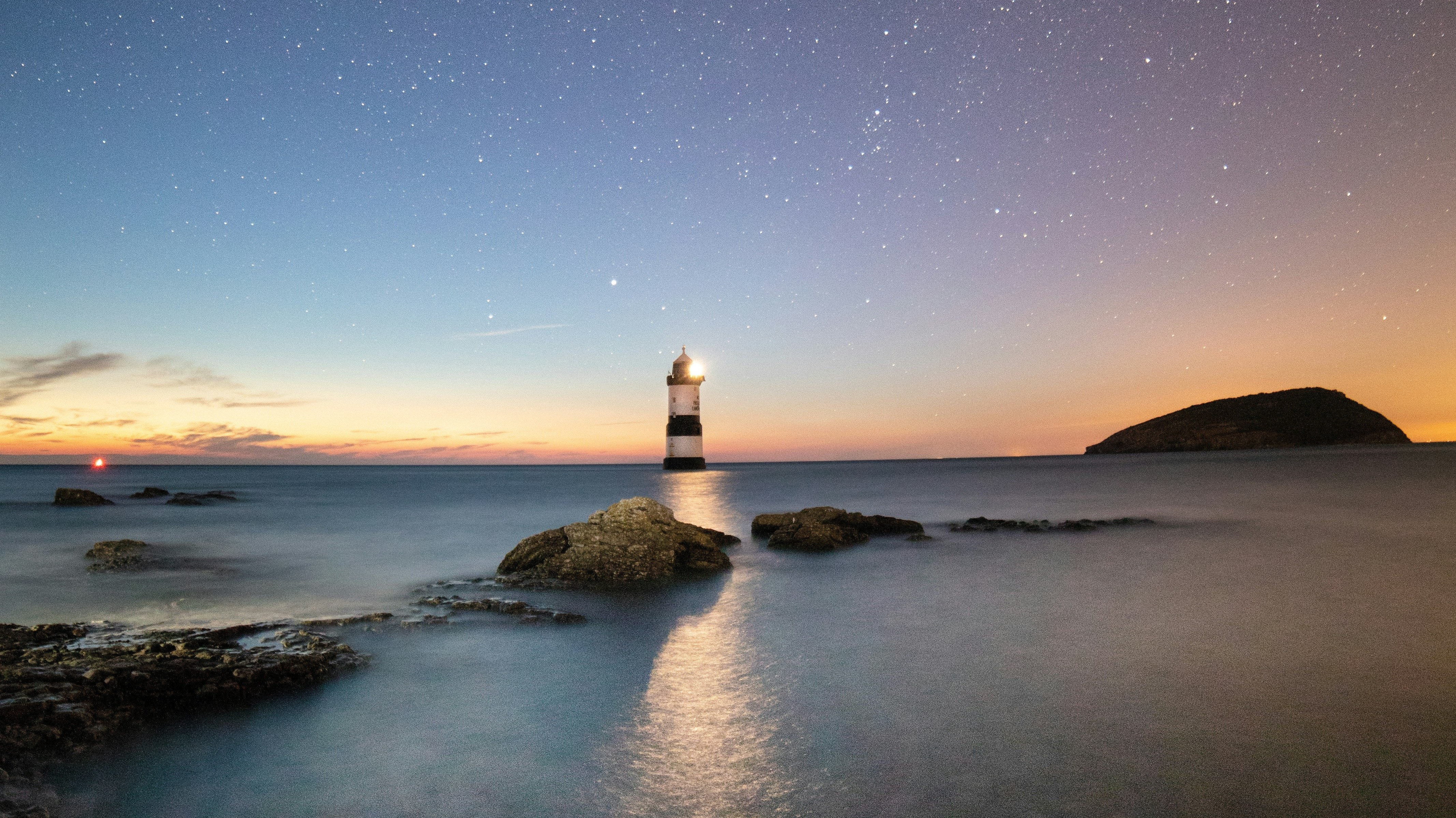 lighthouse against starry sky and sunrise