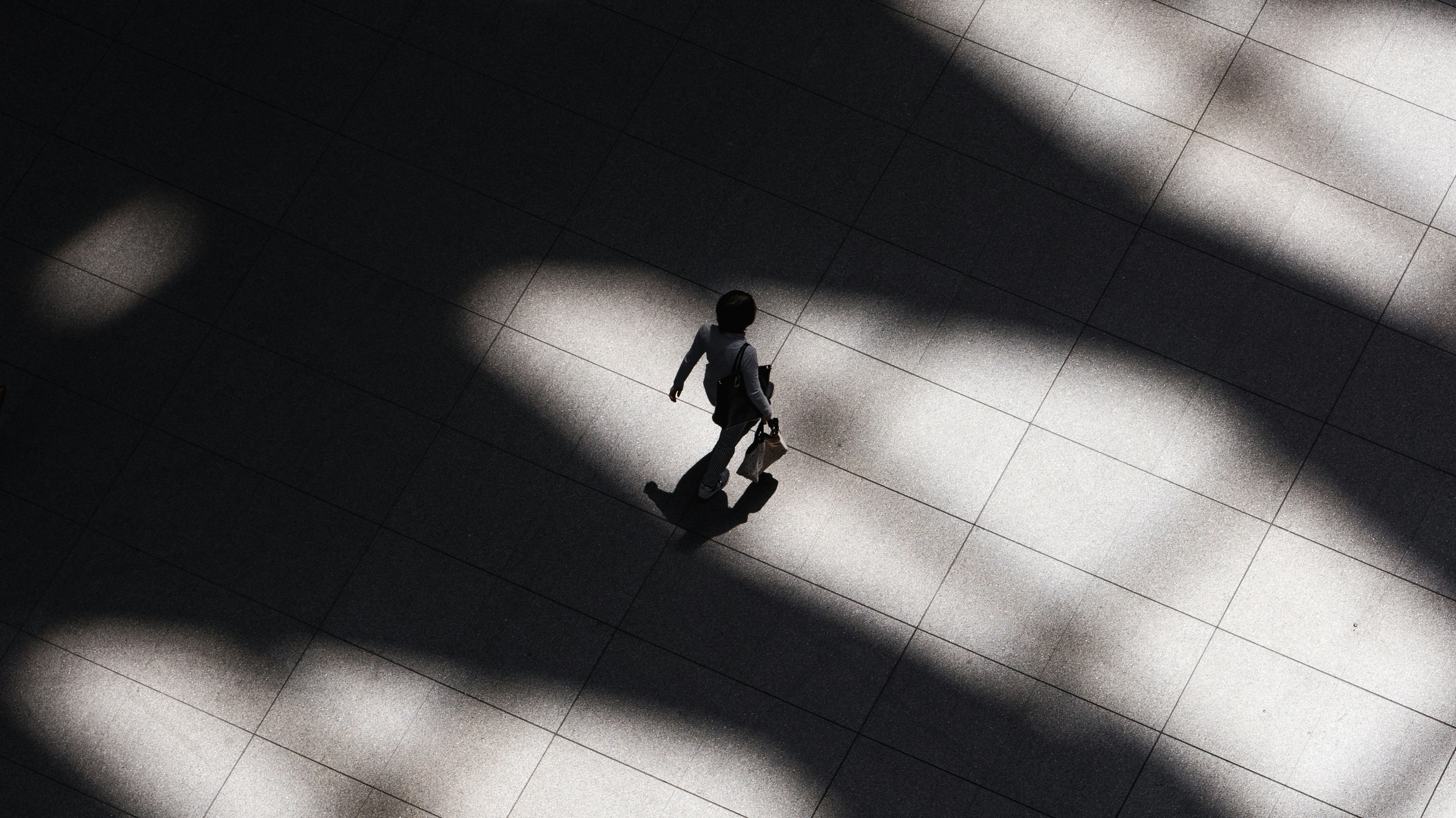 overhead b&w shot of person walking with a briefcase