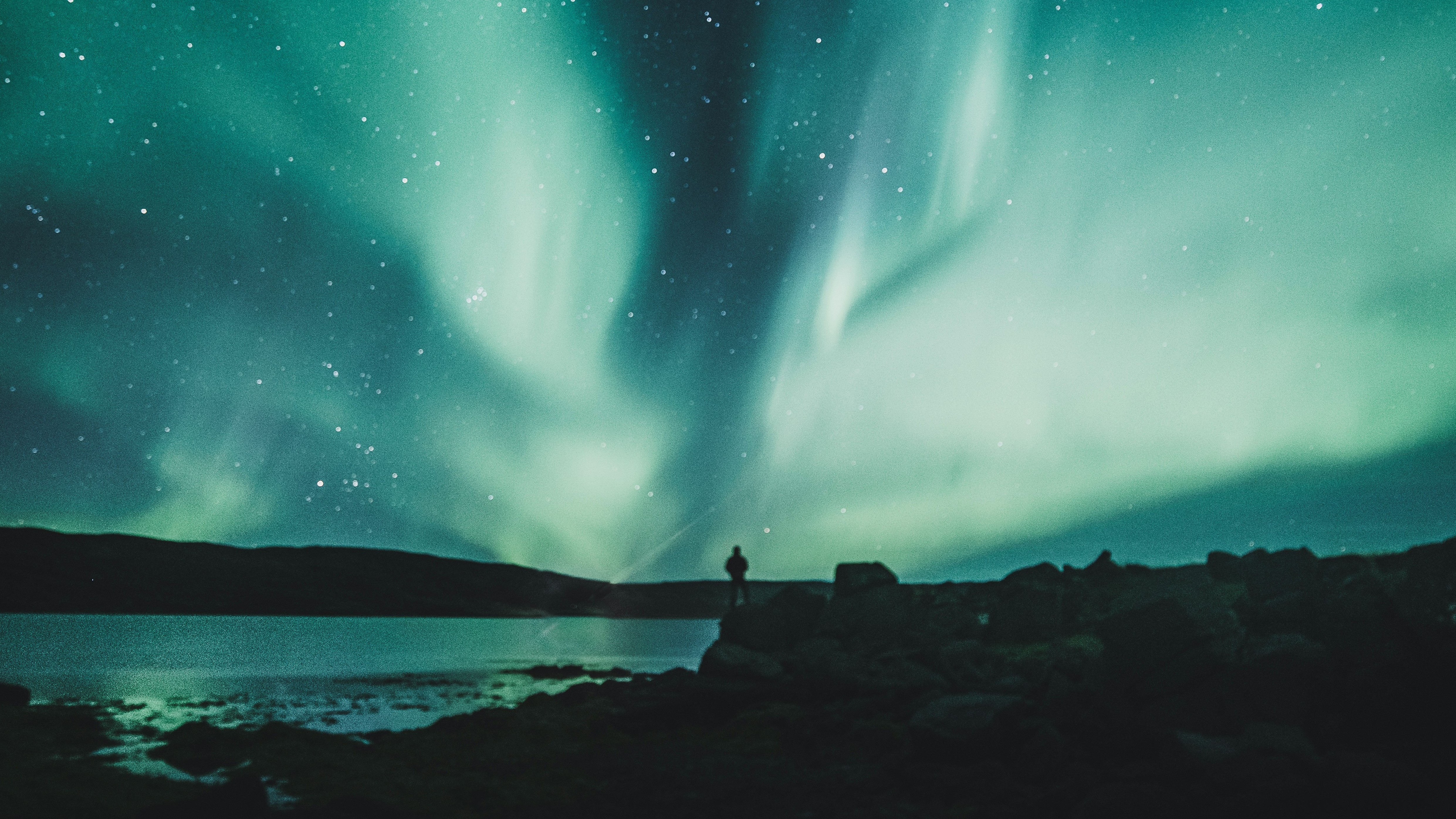 sillouhetted man watching aurora in night sky