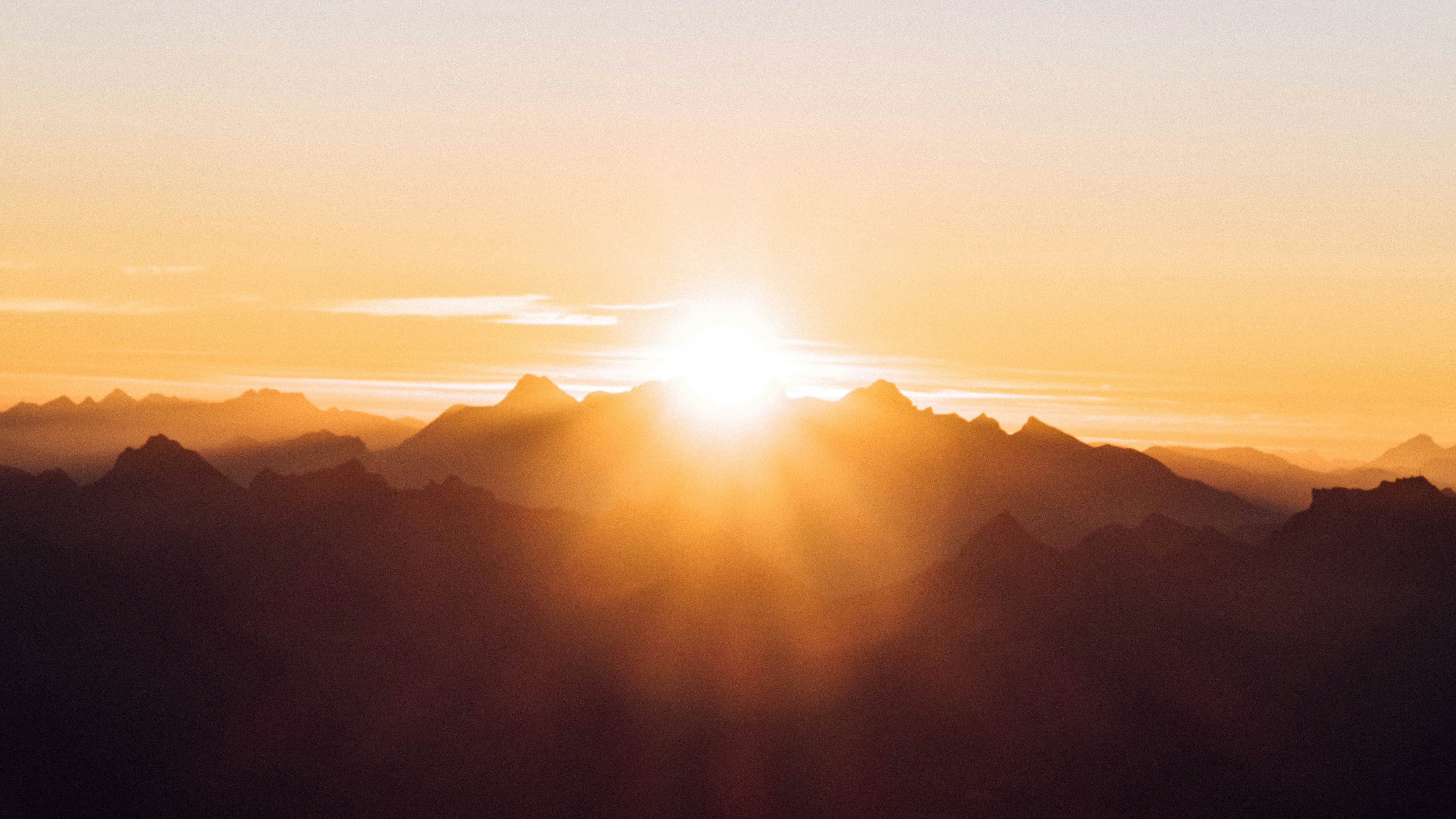 sunlight breaking over orange and yellow mountains