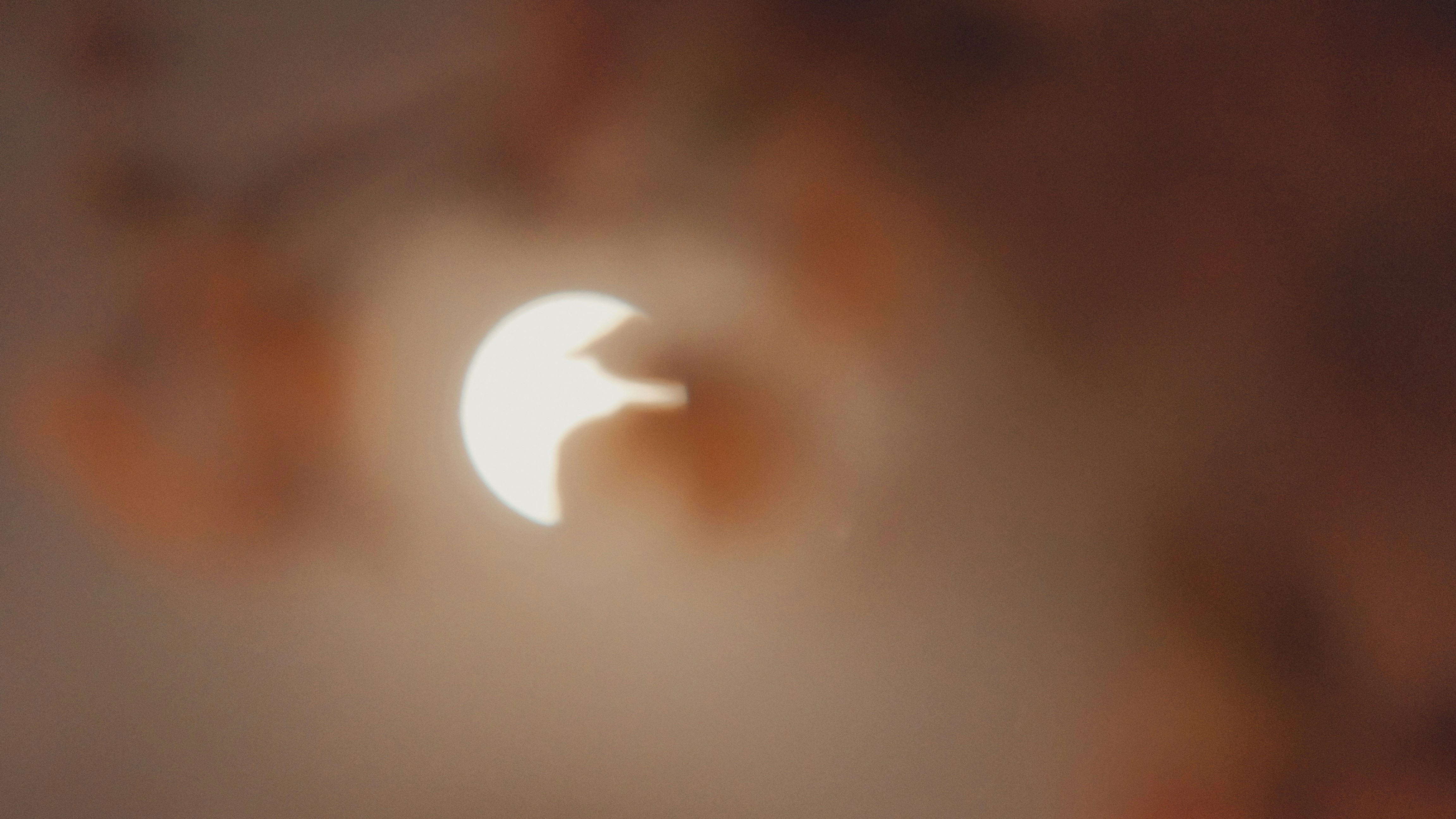 sun eclipsed among pink and orange clouds