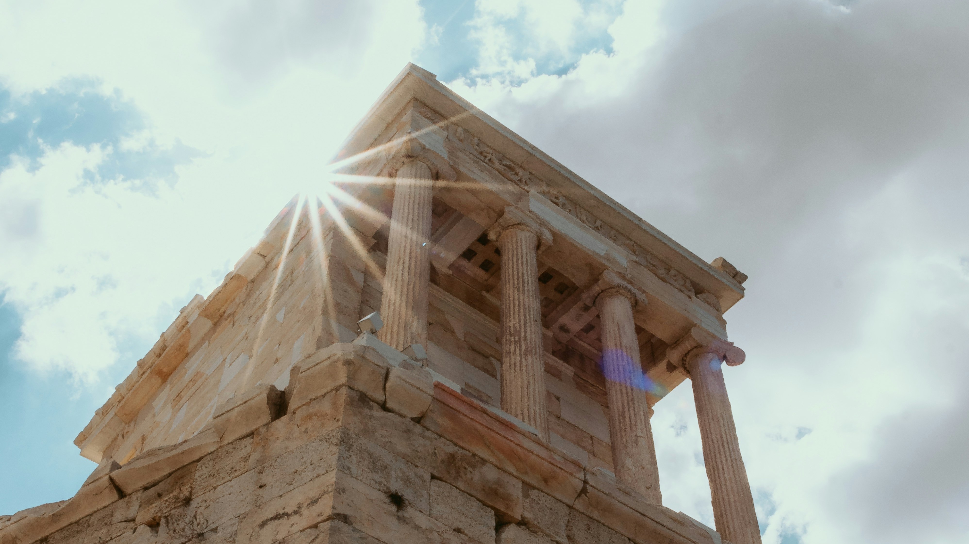 sun behind a greek temple